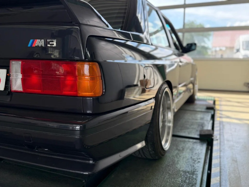 Schwarzer BMW M3 E30 auf einer Hebebühne in der Werkstatt des Autocenters Königsbrunn